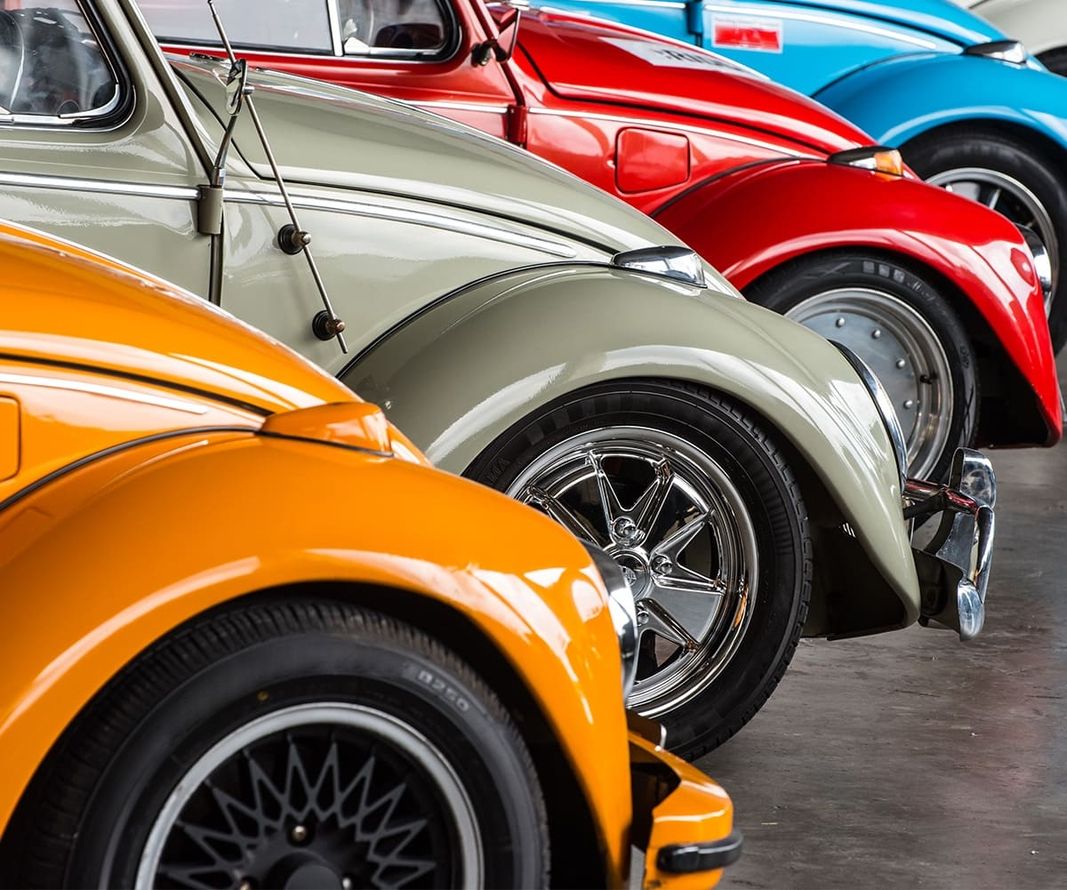 Eine Reihe bunter VW Käfer, ordentlich in einer Garage geparkt, zeigt eine lebendige Farbvielfalt